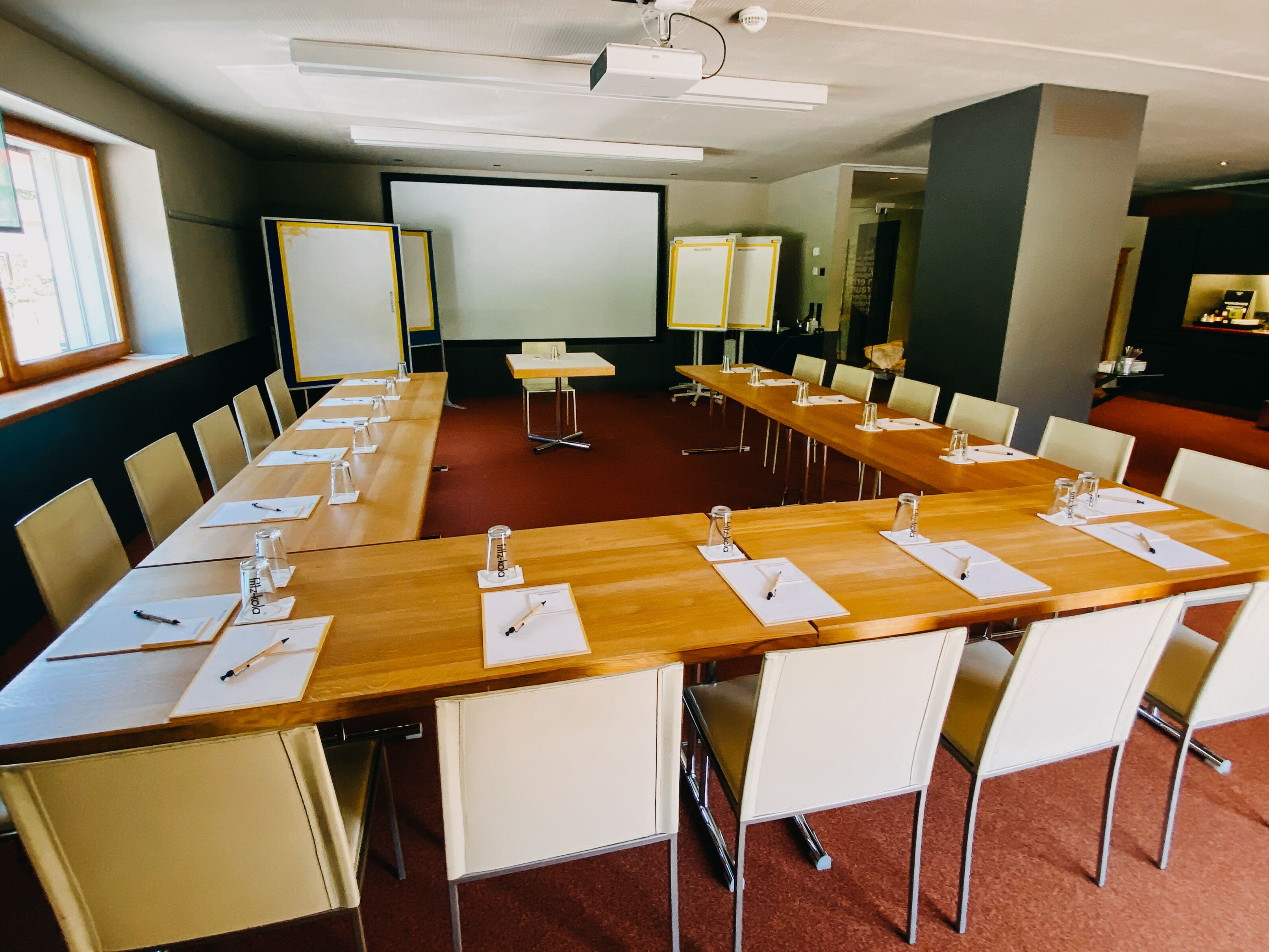 A conference room with a long table, chairs, a projector screen, and a whiteboard.