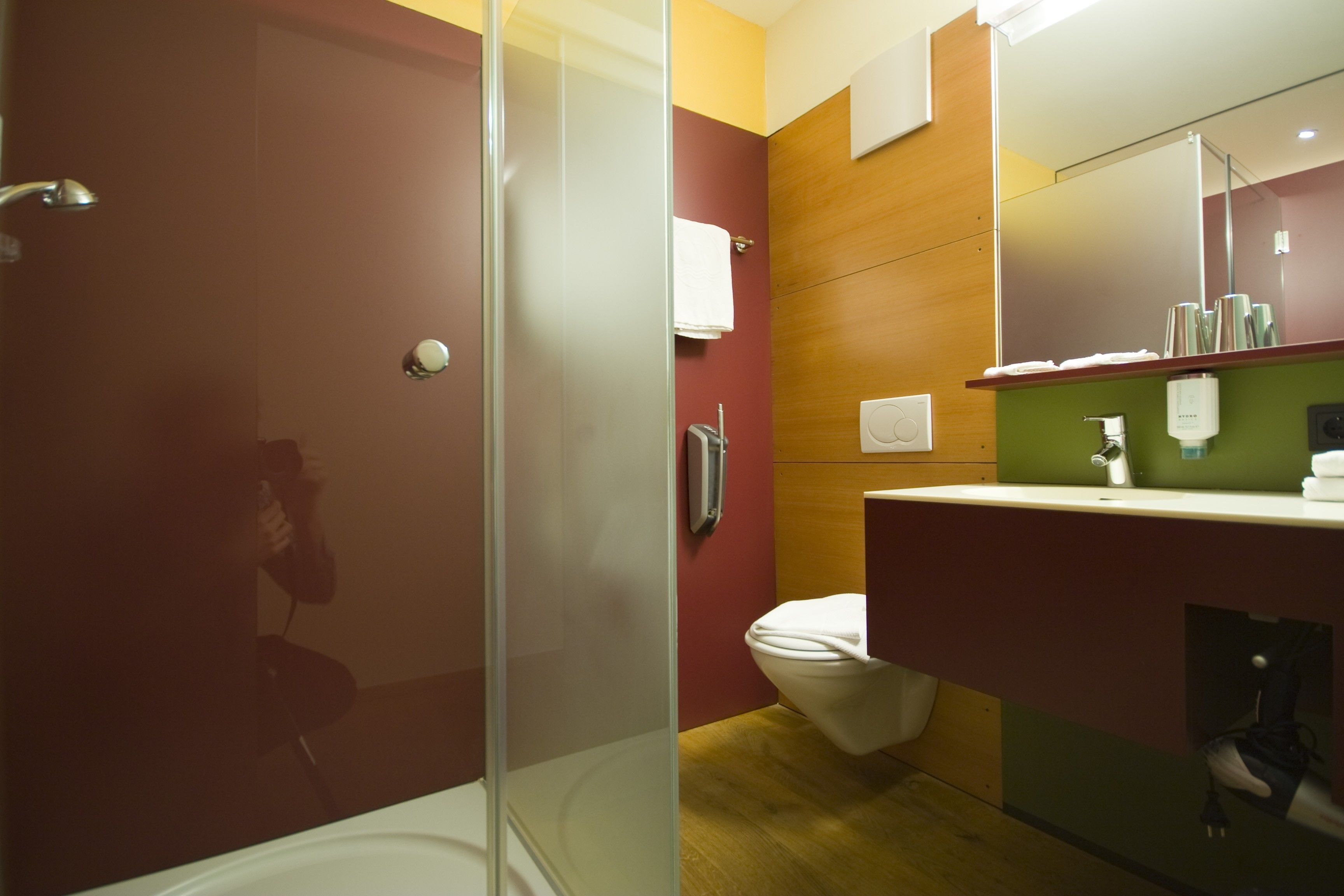 A modern bathroom with a glass shower enclosure, a toilet, and a vanity with a mirror.