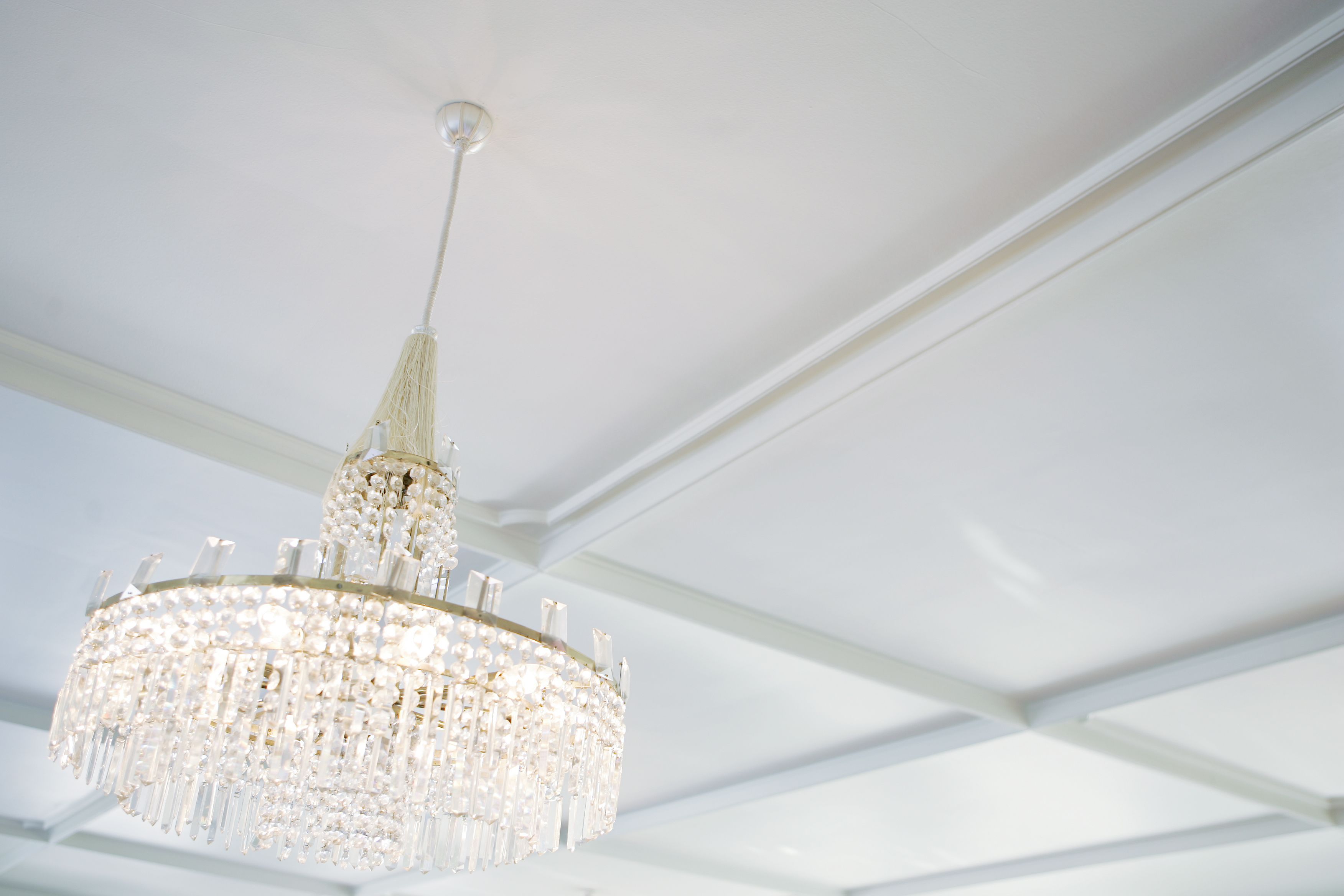 A chandelier with multiple tiers of crystals hanging from a white ceiling.