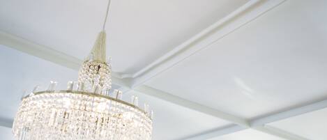 A chandelier with multiple tiers of crystals hanging from a white ceiling.