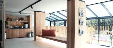 A modern interior with a wooden bench, skylights, and a kitchen area with potted plants.