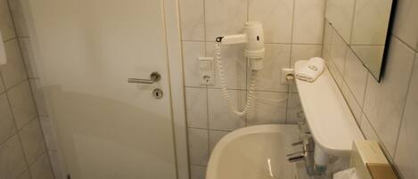 A bathroom with a white sink, a mirror, a towel rack, and a door.