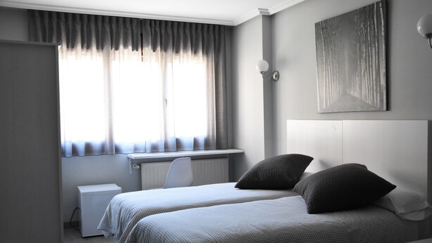 Ein Schlafzimmer mit zwei Betten, einem Schreibtisch und einer Heizung.