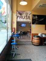 Un interior con mesas, sillas, un extintor, un televisor y un barril de madera.