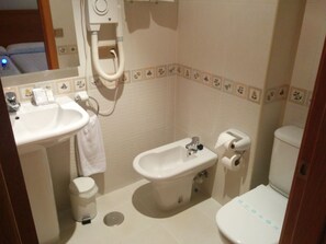 A small bathroom with a sink, bidet, toilet, and a trash can. - Hotel Carbayón (Oviedo)
