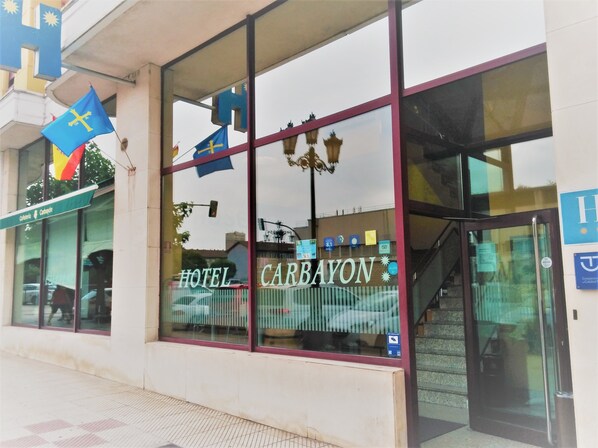 A hotel entrance with large windows, a visible staircase, and a flag outside. - Hotel Carbayón (Oviedo)