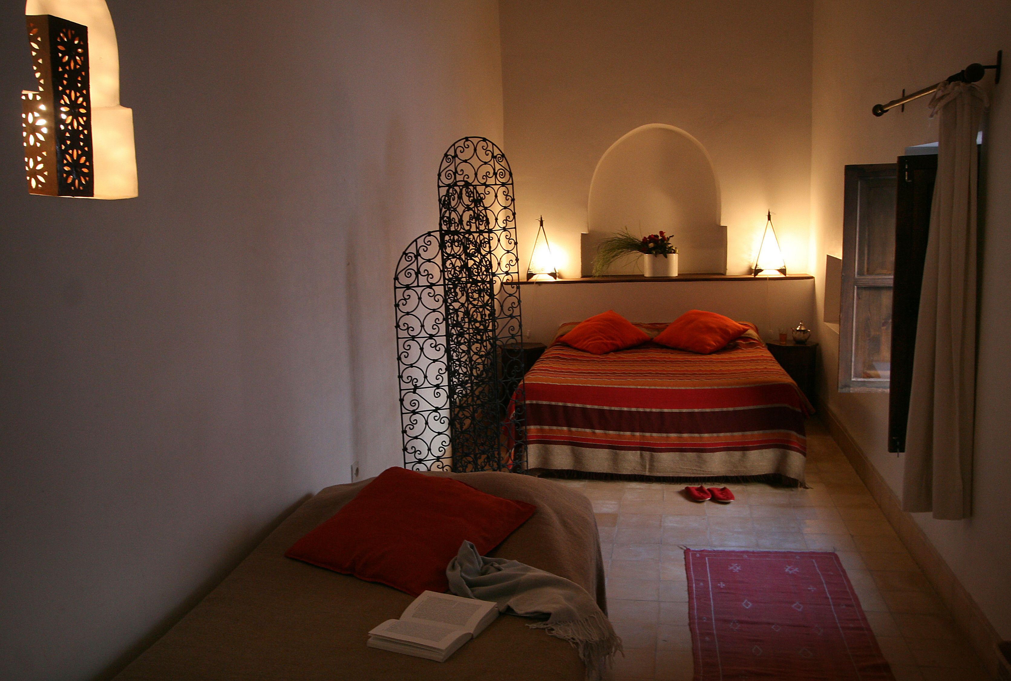 Une chambre confortable avec un lit, une table de chevet, une commode, un élément décoratif mural et une fenêtre avec des rideaux.