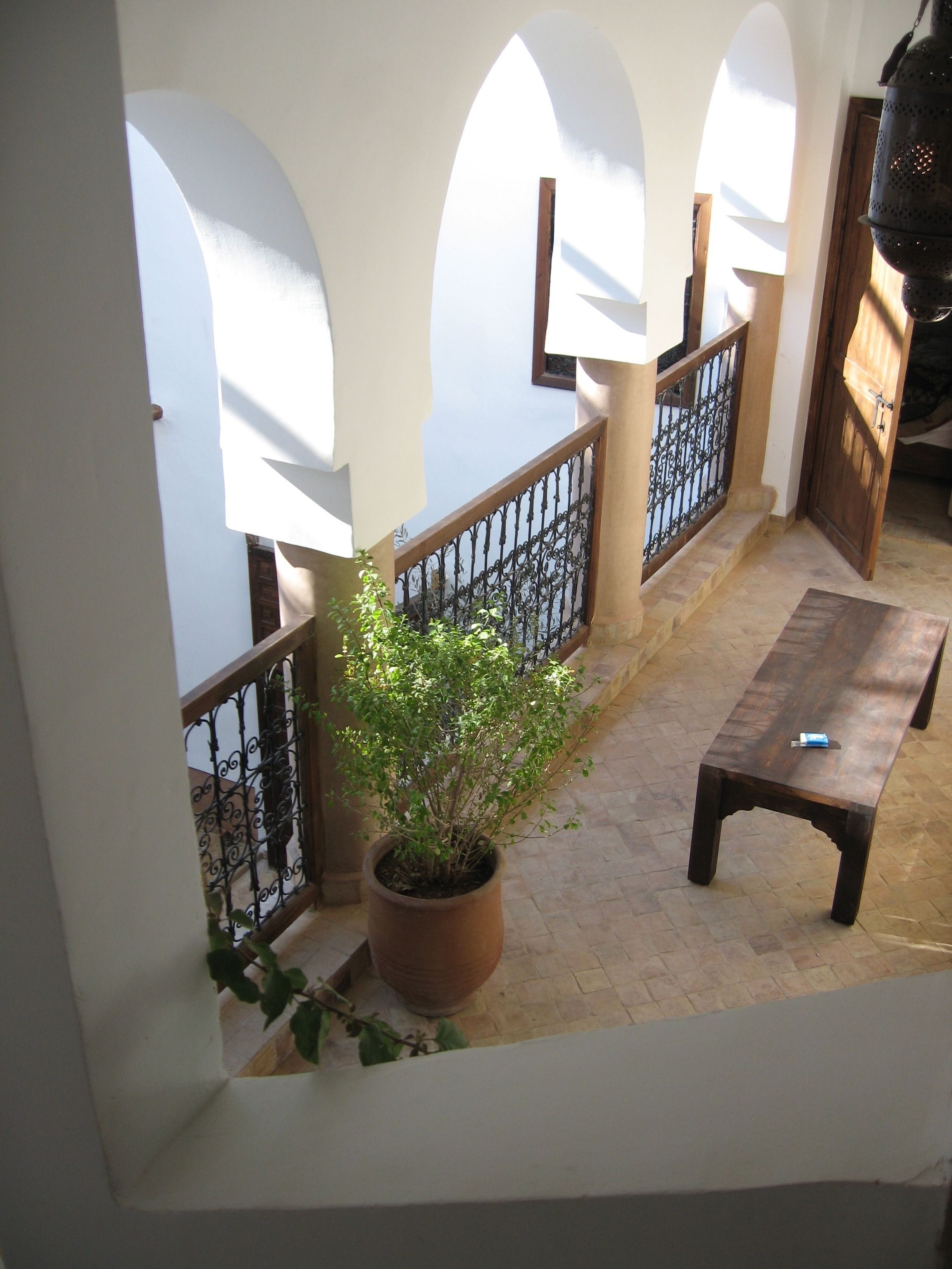 A balcony with a potted plant, a wooden bench, and a metal railing.
