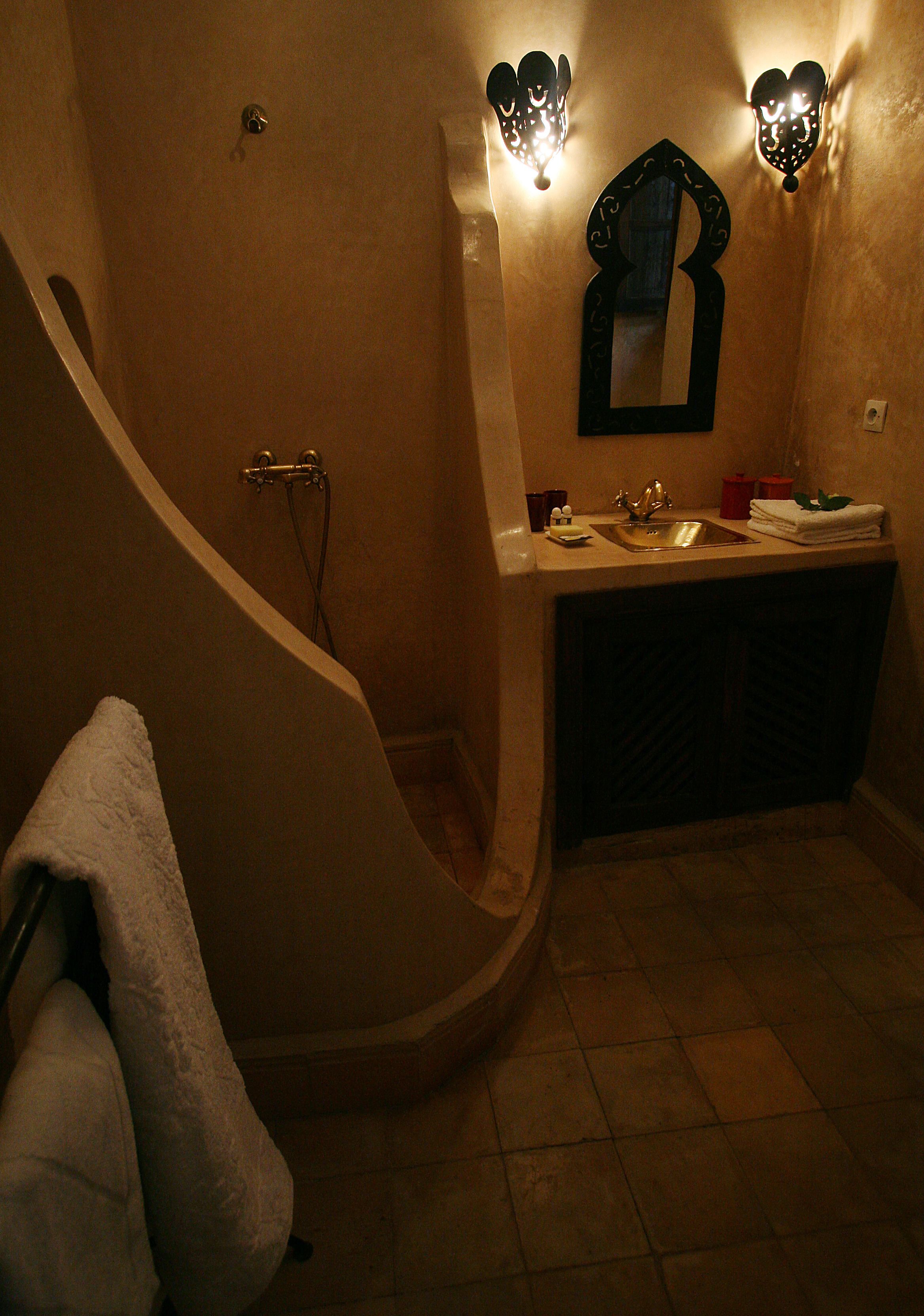 A bathroom with a curved bathtub, a sink, and two wall-mounted lights.