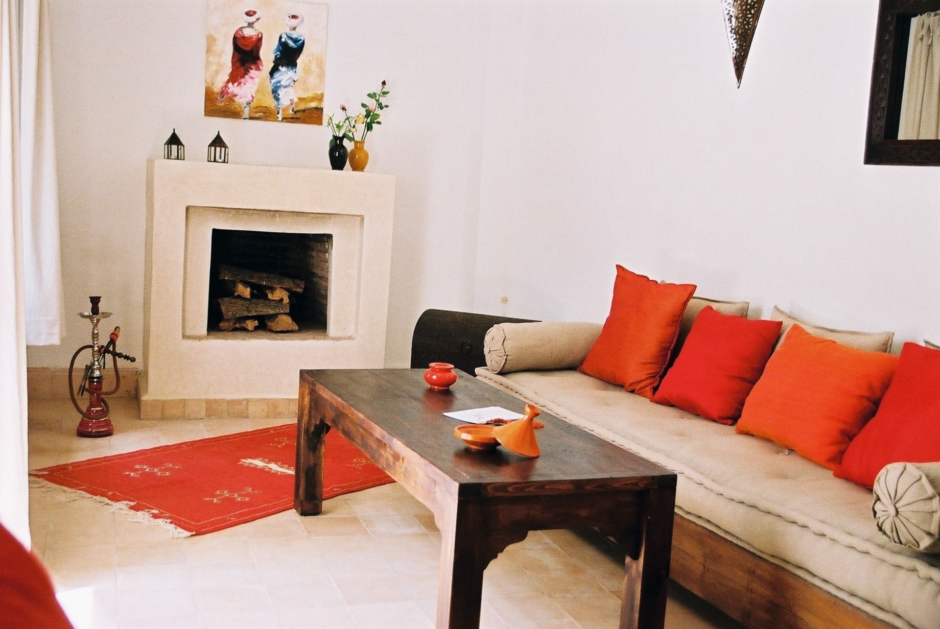 A living room with a sofa, red cushions, a wooden coffee table, a fireplace, and a red rug.