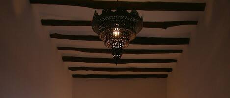 A dimly lit bedroom with a bed, a decorative wall arch, and a hanging light fixture.