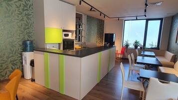 Una cocina moderna con una isla central, un comedor con sillas blancas y un amplio ventanal que ofrece luz natural.