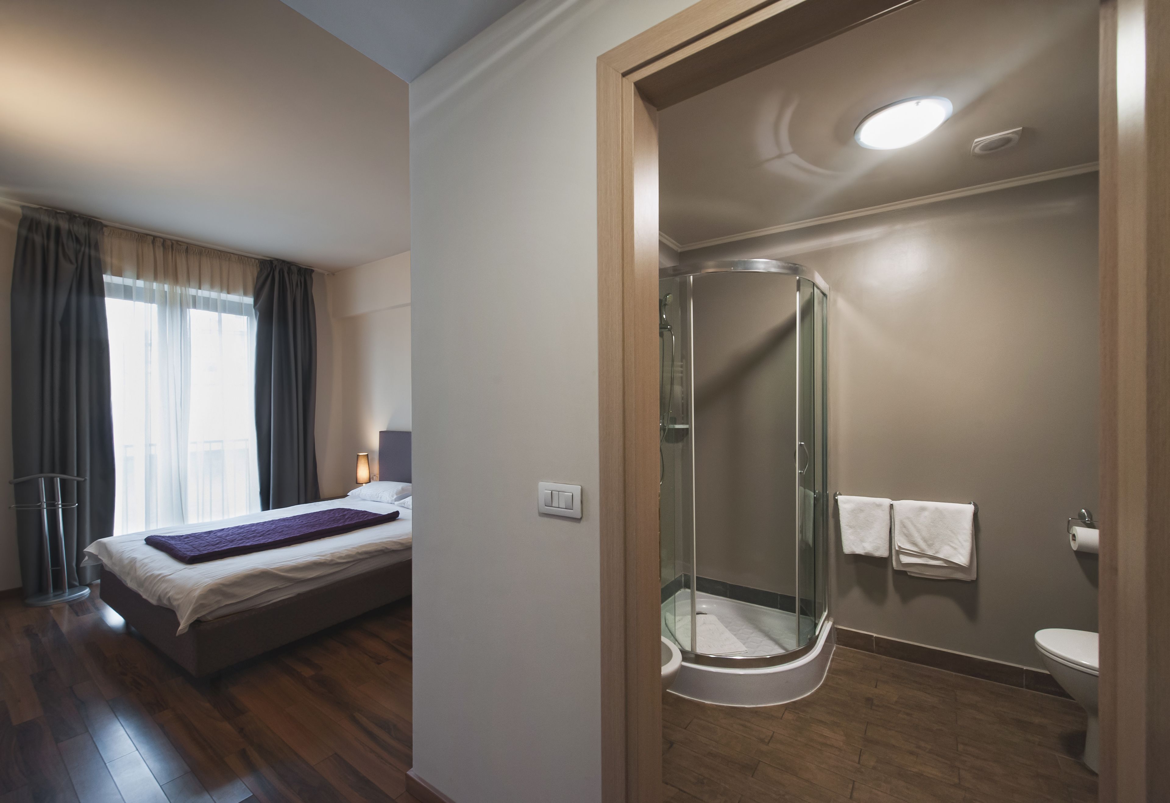 A bedroom with a bed, a bedside table, and a window with curtains.