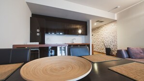 A modern kitchen with dark cabinets, a central island, and a dining area with a round table and chairs.
