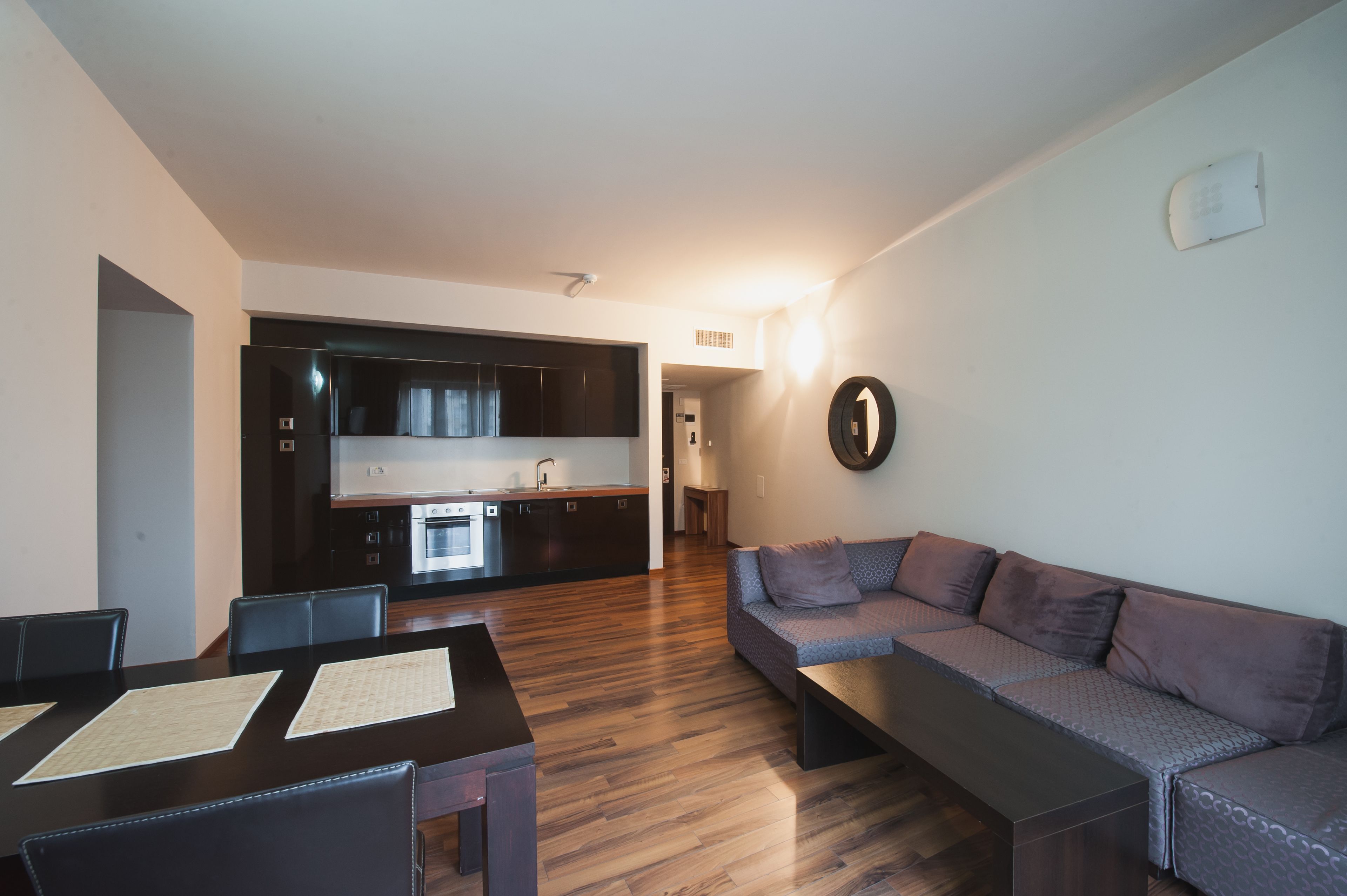 A modern living space with a kitchen, dining area, and a sofa.