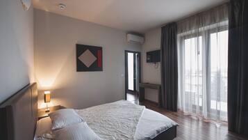 Une chambre d’hôtel équipée d’un lit, d’une lampe de chevet, d’un climatiseur et d’un téléviseur fixé au mur.