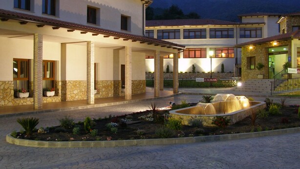 Un patio de hotel con una fuente, muros de piedra y una zona de estar cubierta.
