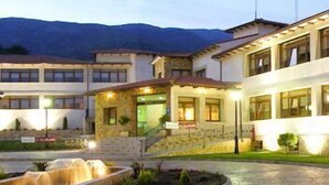Un hotel con un patio, una fuente y montañas al fondo.