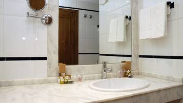 Un baño con un espejo grande, azulejos blancos, una puerta de madera y un lavabo blanco.