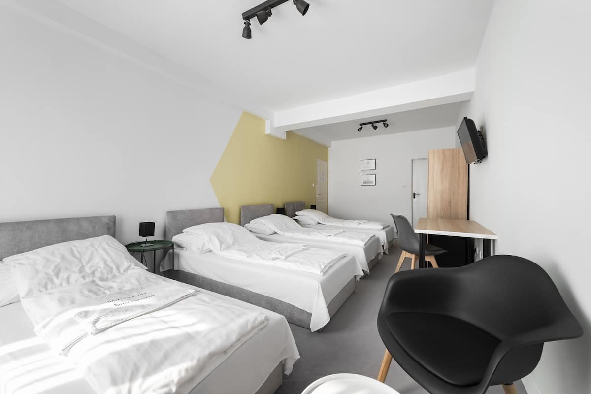 A modern hotel room with two beds, a desk, and a chair.