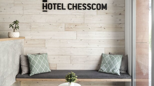 Un moderno vestíbulo de hotel con una pared de madera, un área de descanso con cojines y dos mesitas.