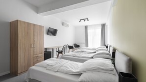 Una habitación de hotel moderna con dos camas, un armario de madera, un escritorio con sillas y un televisor.