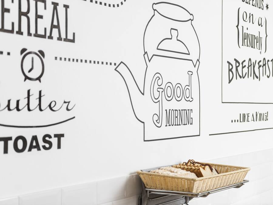 A wall with a cereal and butter toast sign, a teapot, and a basket of toast.