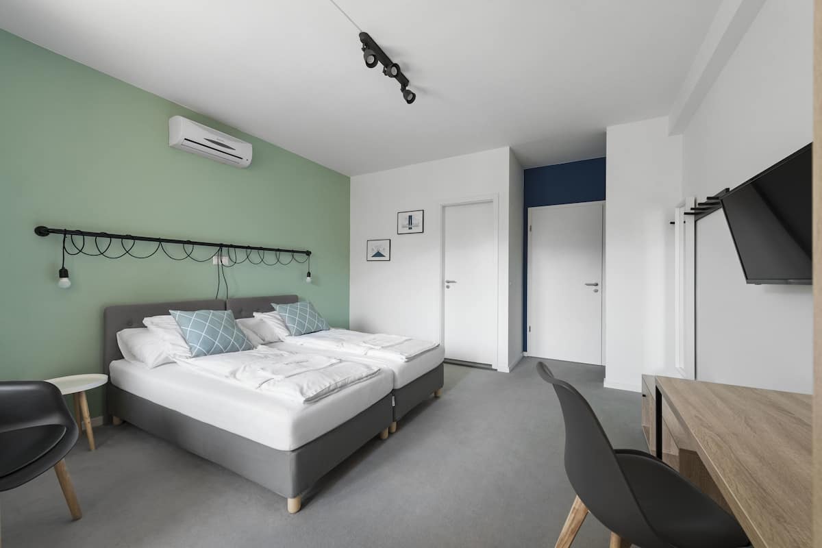 A modern bedroom with a bed, bedside tables, a desk, and a TV.