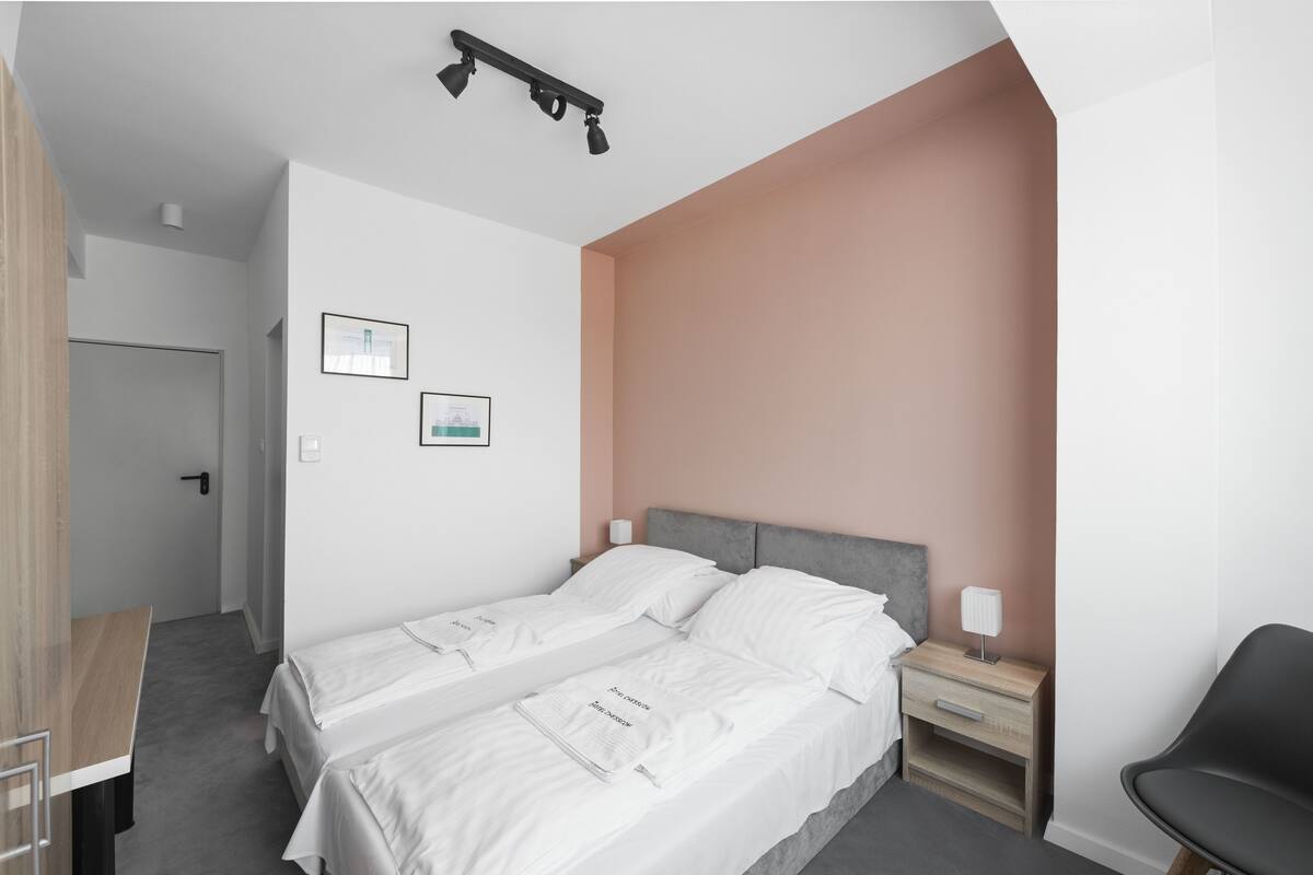 A modern hotel room with a large bed, bedside tables, and a desk.