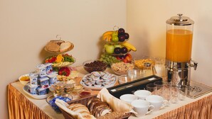 Ett buffébord med olika sorters mat, inklusive frukt, bröd och drycker.