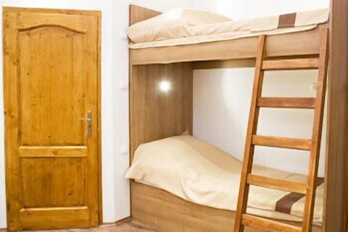Kerrossänky, jossa on puinen tikapuut, puinen ovi ja puinen lattia.