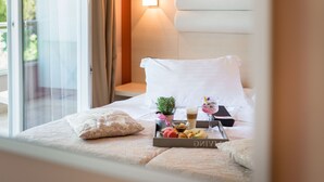 A hotel room with a bed, a tray with food and drinks, a small plant, and a nightstand with a lamp. - Hotel Maritimo (Makarska)