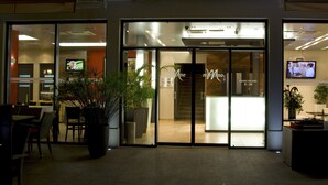 A hotel entrance with a reception desk, indoor plants, and a TV displaying a program. - Hotel Maritimo (Makarska)