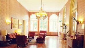 A spacious lobby with a large chandelier, comfortable seating, and large windows allowing natural light. - Grand Hotel Regina (Salsomaggiore Terme)