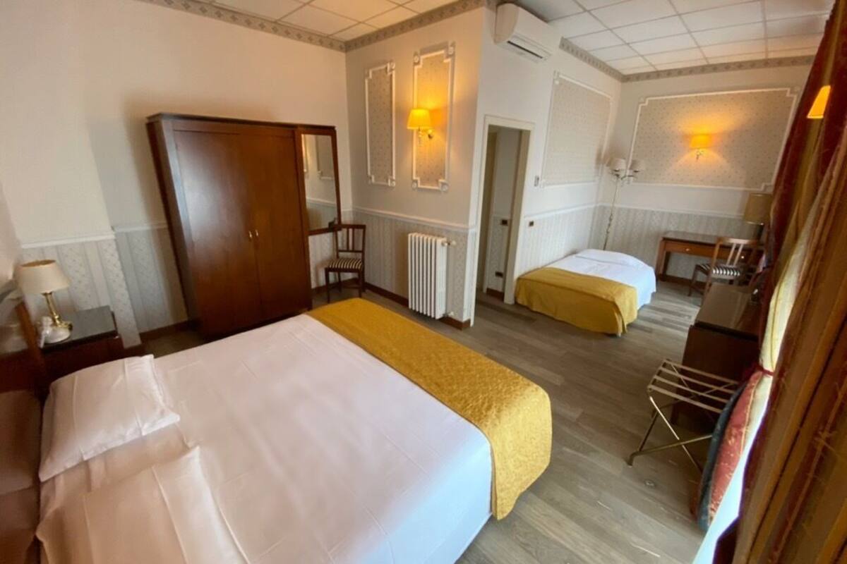 A hotel room with two beds, a wardrobe, a desk, and a chair.