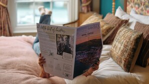 A person reading a magazine on a bed with a window in the background. - Royal Castle Hotel (Dartmouth)