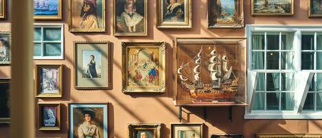 Un mur orné de divers tableaux encadrés, notamment des portraits et des scènes maritimes.