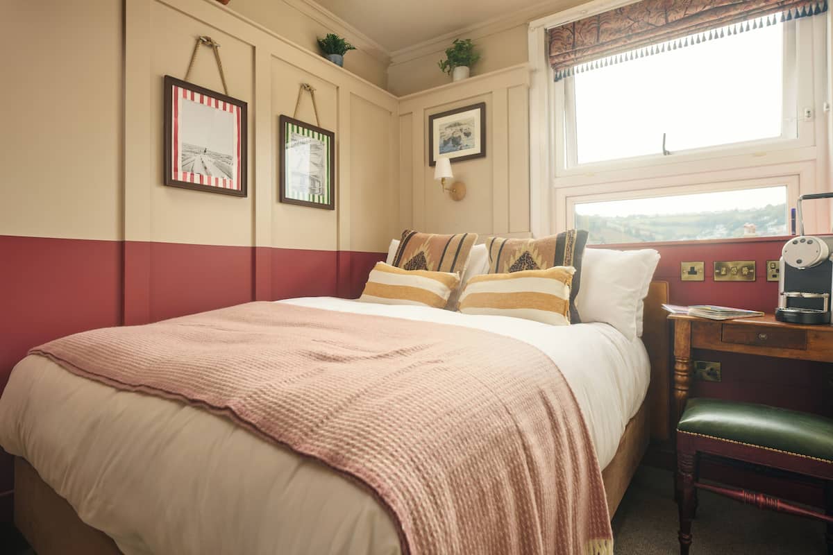 A bedroom with a bed, a nightstand, a chair, and a window with a view.
