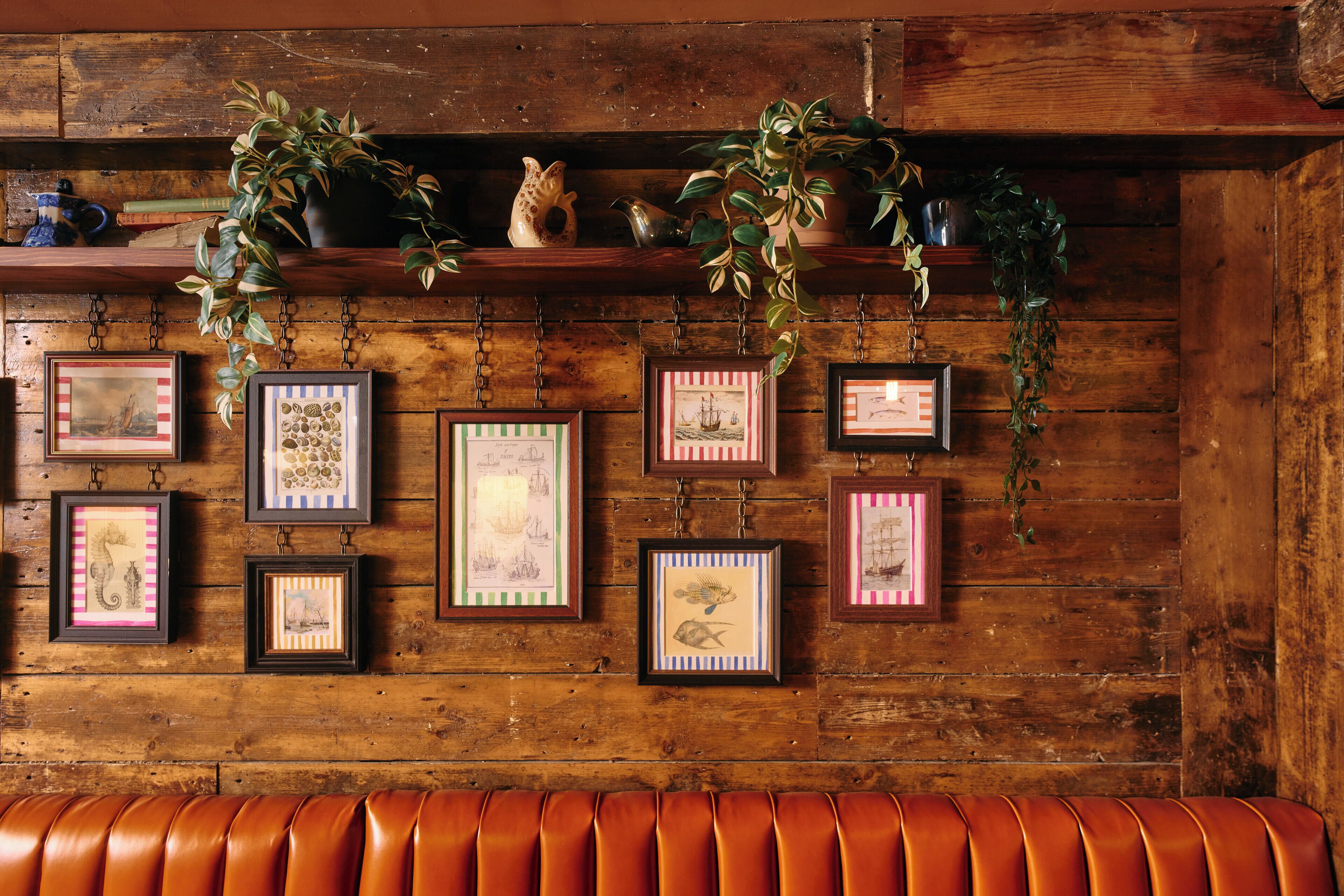 A wooden wall with framed pictures and a leather bench.