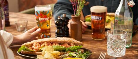 Ein Esstisch mit einem Sandwich, Chips und einem Getränk.