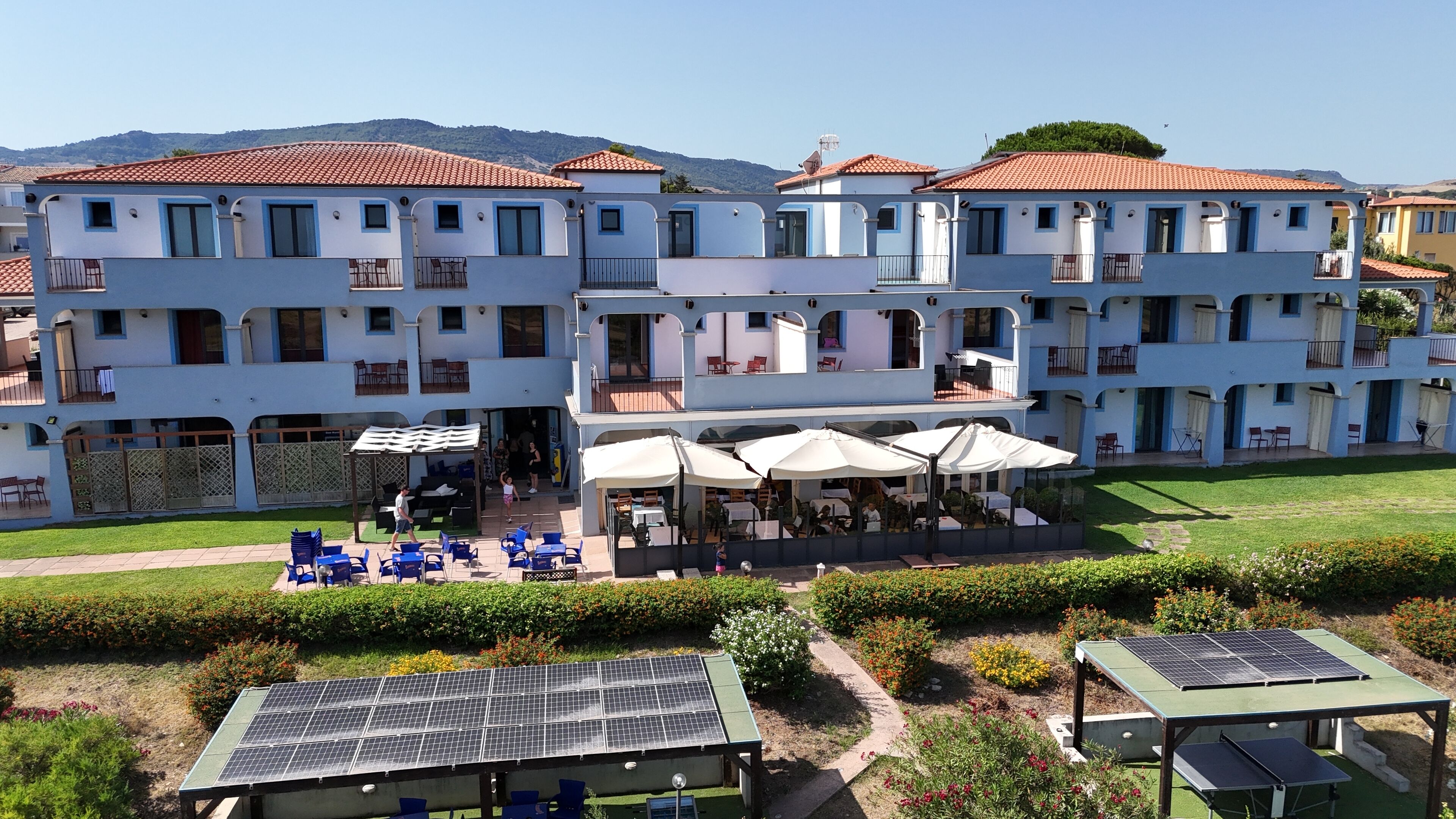 A multi-story hotel with outdoor seating and solar panels.