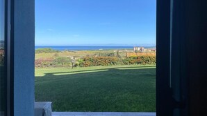 Vista desde un balcón con cielo despejado y un área verde al frente.