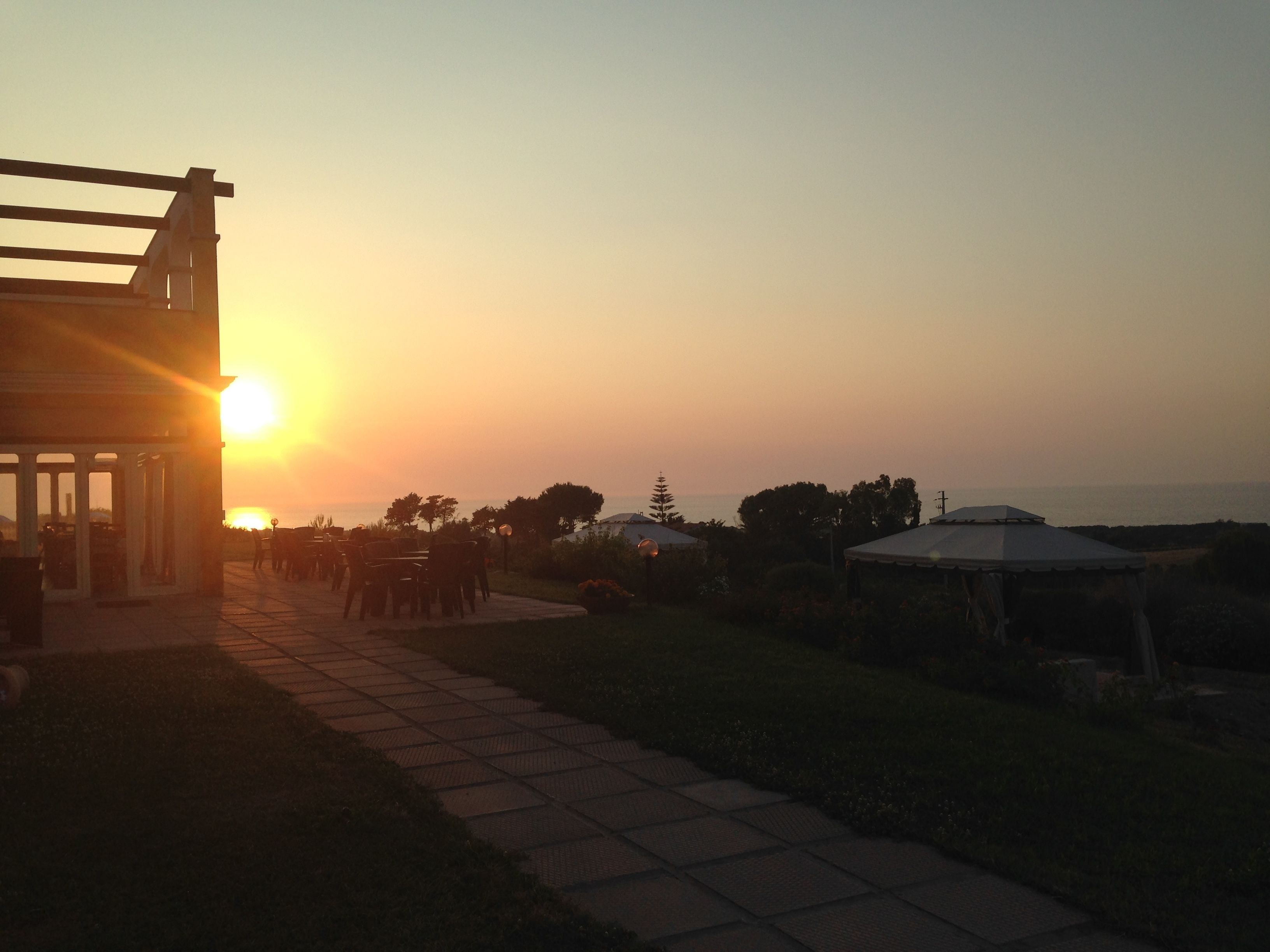 A patio area with outdoor seating and a view of the sunset.