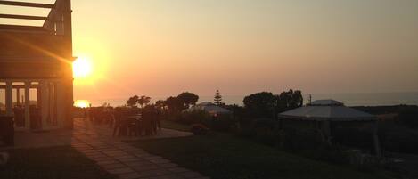 A patio area with outdoor seating and a view of the sunset.