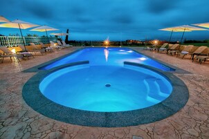 Una piscina al aire libre, sombrillas, tumbonas