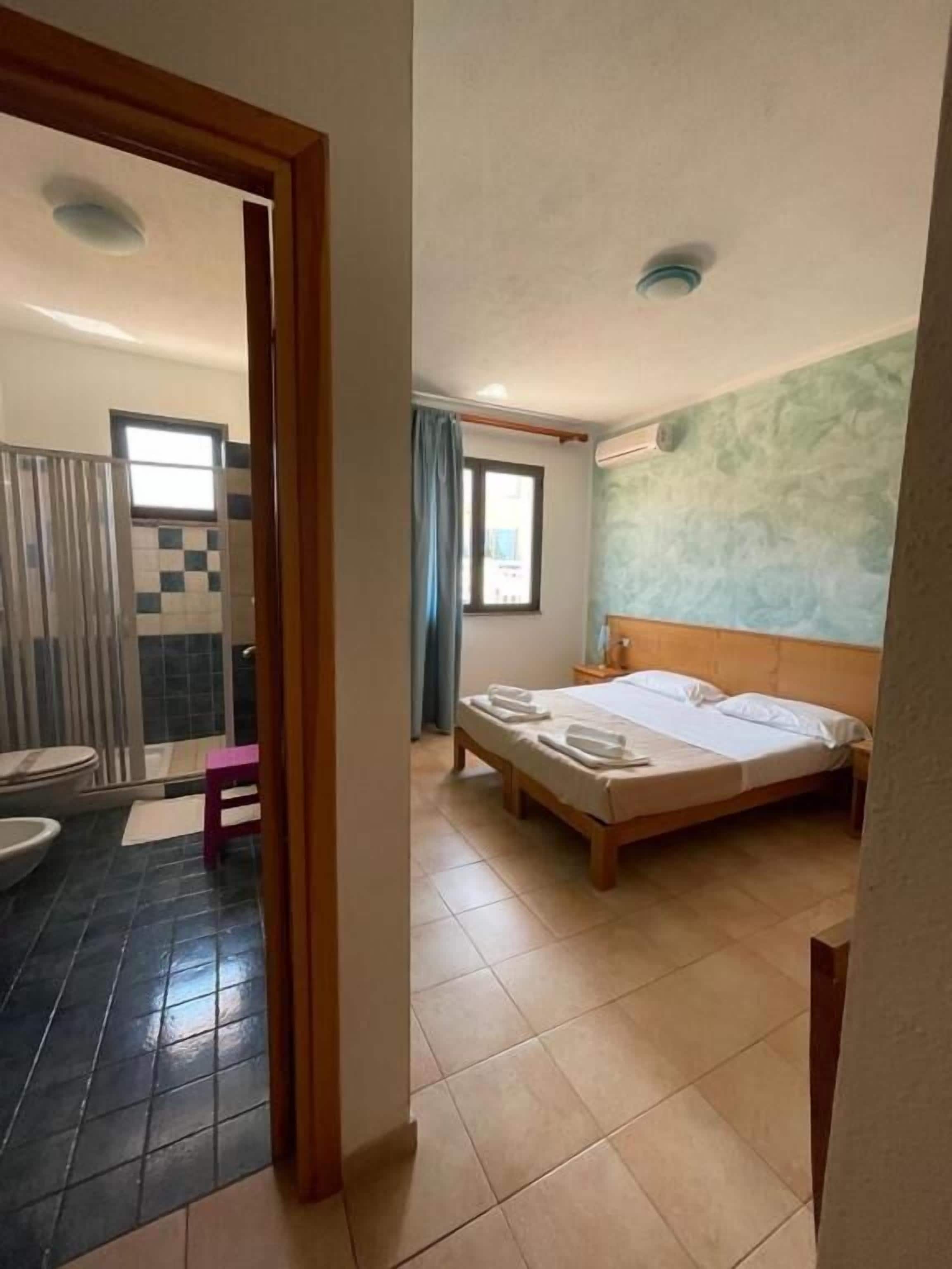 Une chambre d’hôtel avec un lit, une salle de bain avec douche et une vue sur l’extérieur.