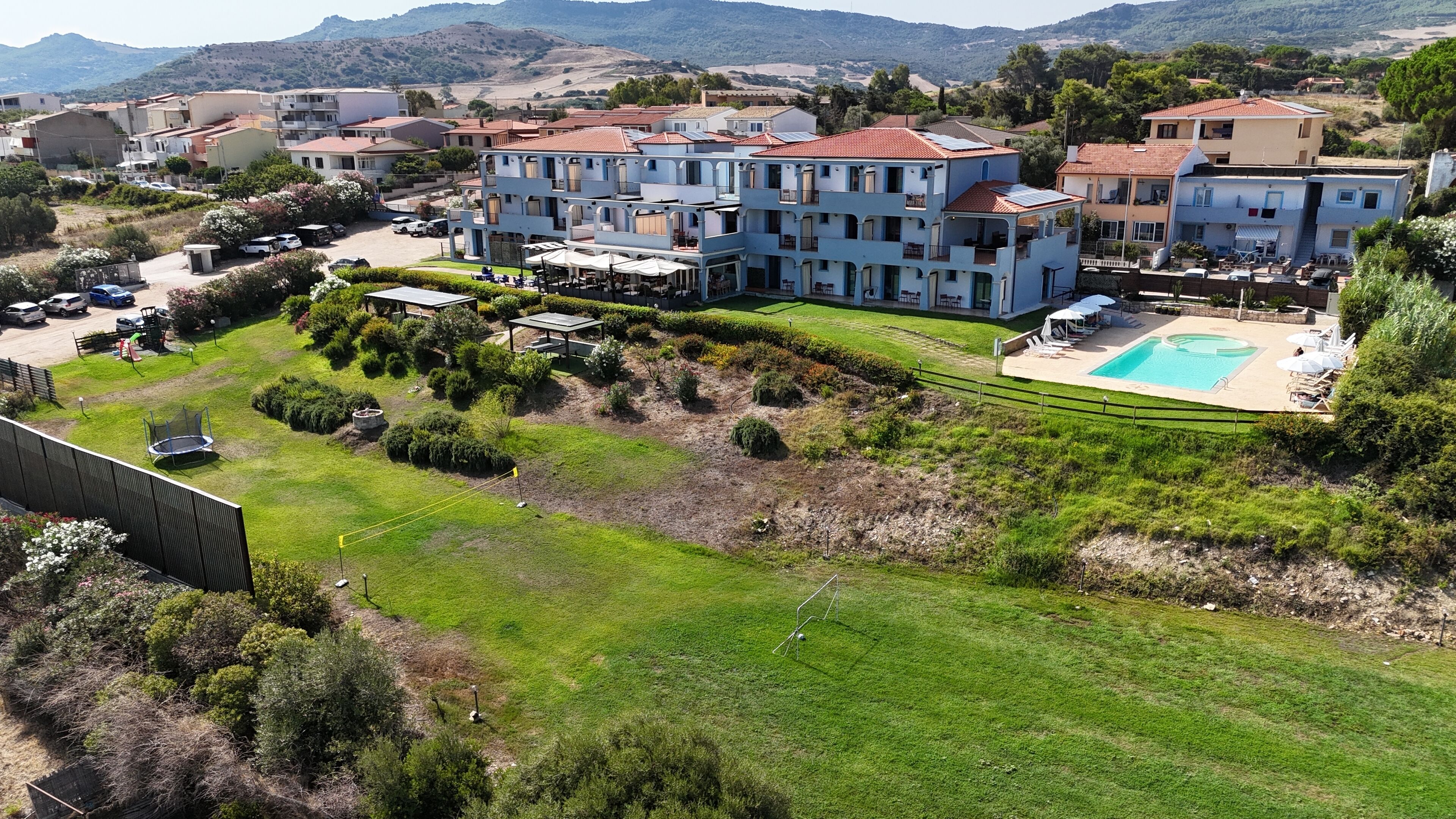 Un hotel de varios pisos con piscina, zona de estar al aire libre y jardín ajardinado.