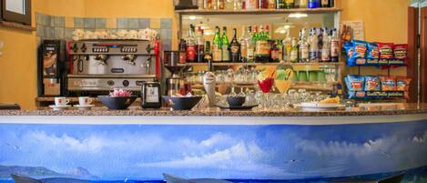 A bar area with a coffee machine, shelves of liquor bottles, and bar stools.