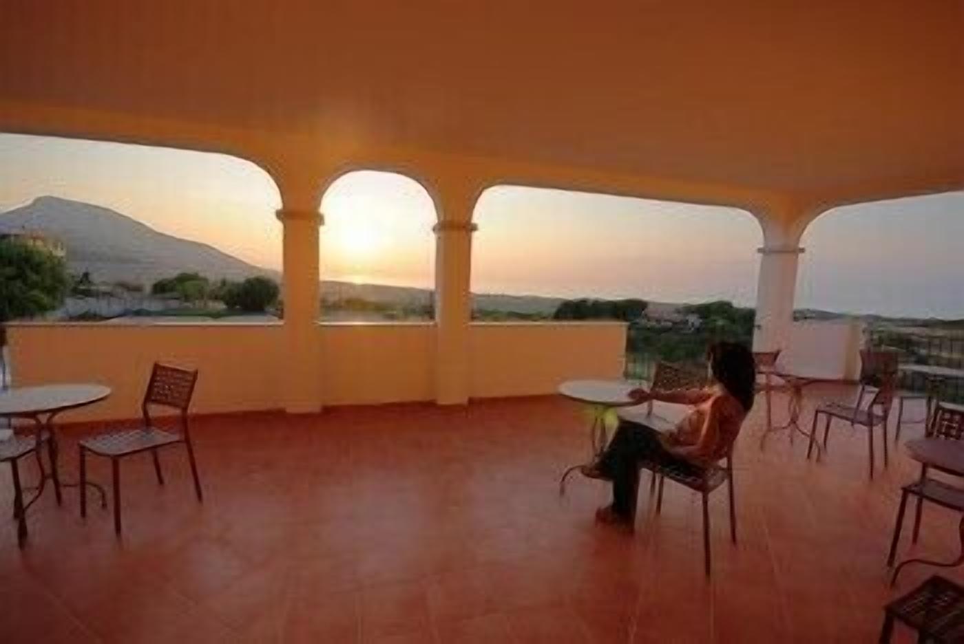 A terrace with a view of a mountain, featuring a person seated at a table.