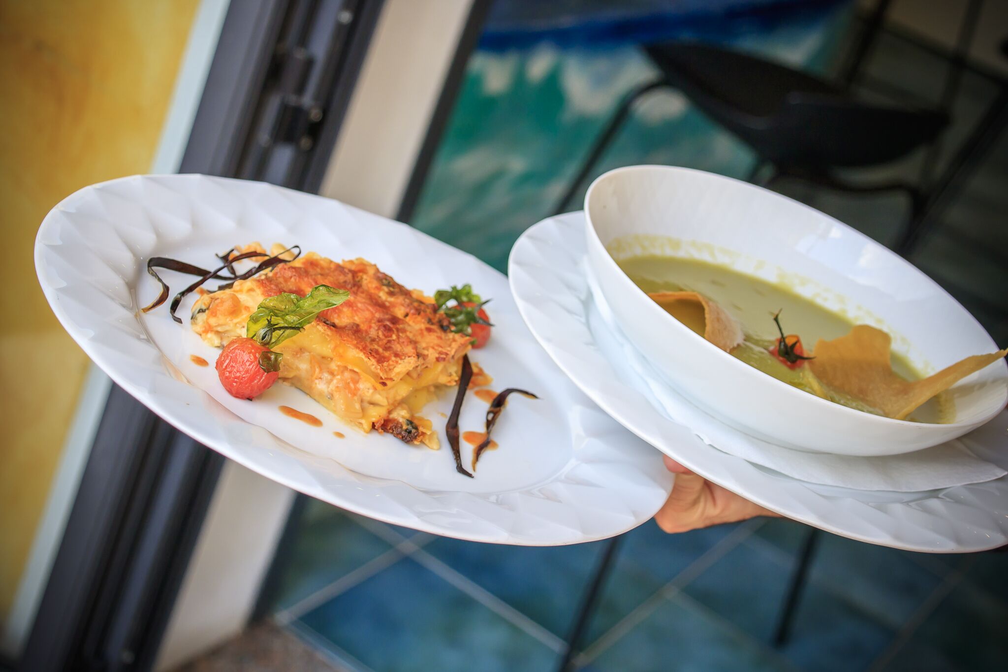 Uma pessoa segurando dois pratos, um com um prato de comida e outro com uma tigela.